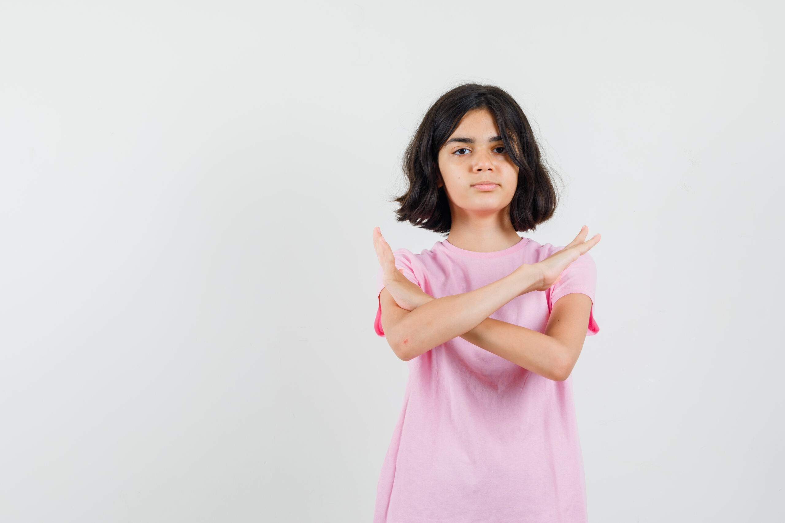 Little girl showing refusal gesture in pink t-shirt and looking resolute. front view.